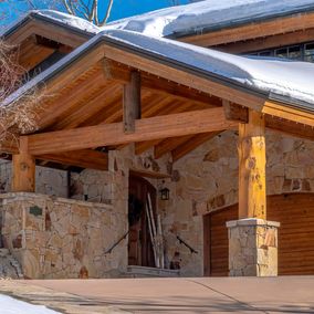 A snowy entrance to a wood frame home in Park City.